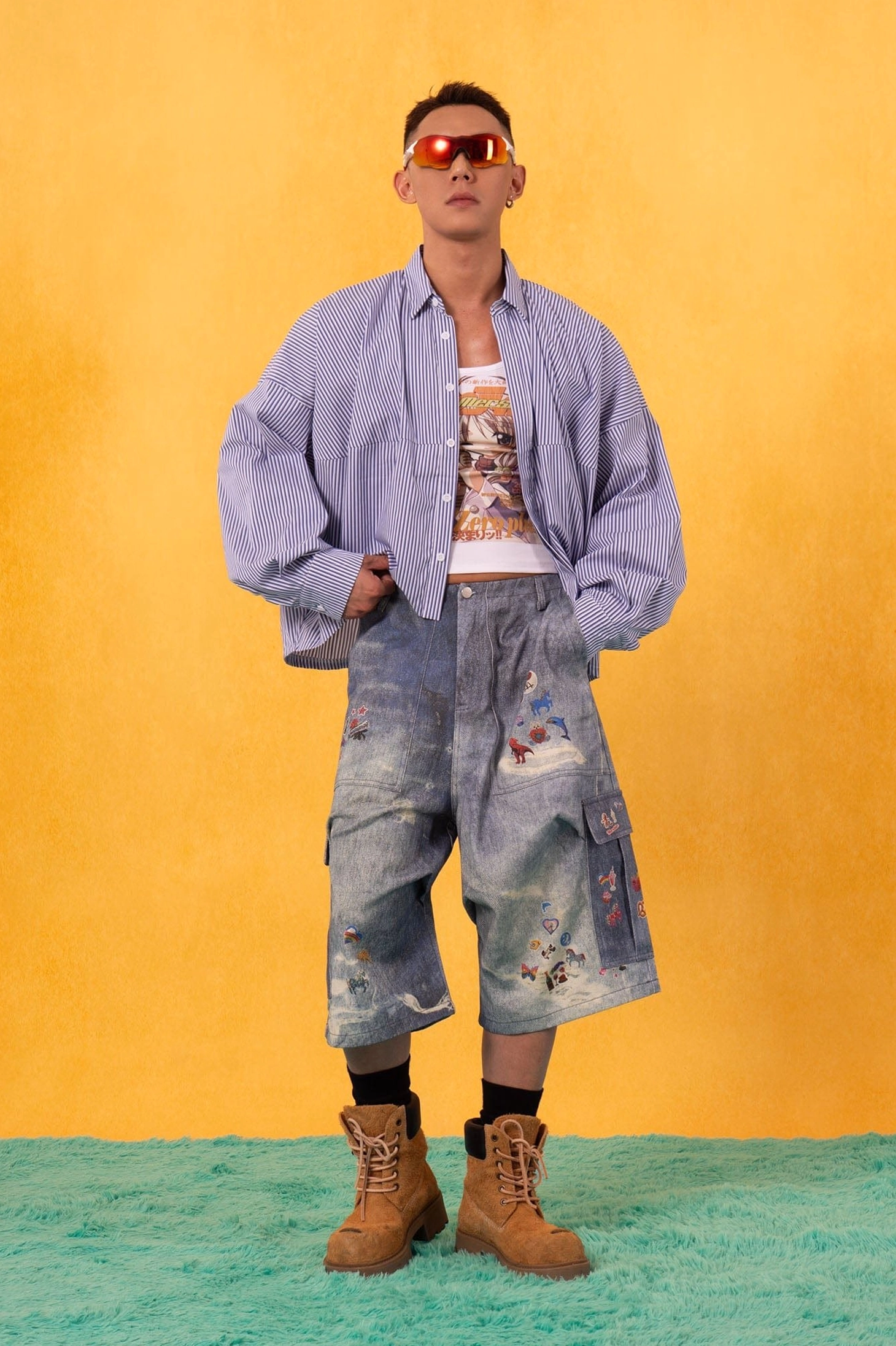 Light blue pinstripe cropped poplin shirt layered over a graphic tank top with distressed cargo denim shorts