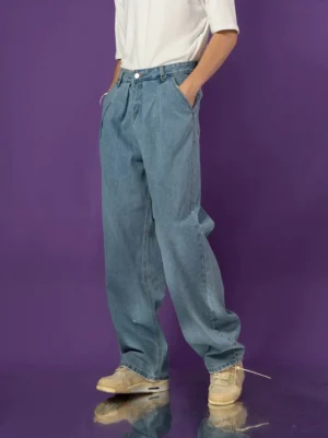 Light blue pleated barrel-leg jeans front view styled with white t-shirt and beige sneakers in a purple studio