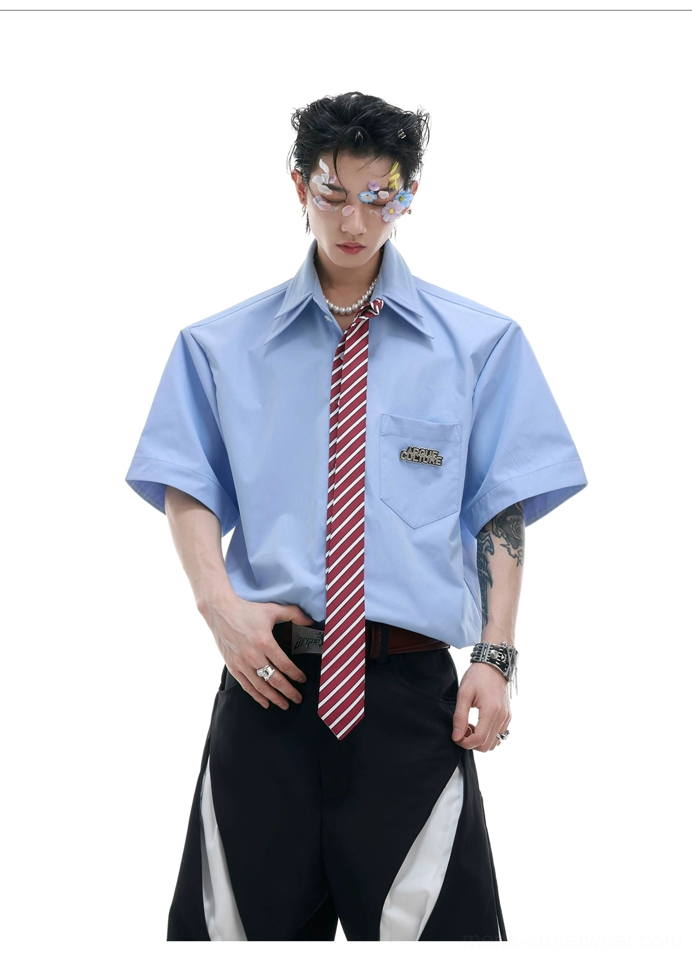 Close up of light blue short sleeve shirt with orange red striped tie and silver accessories