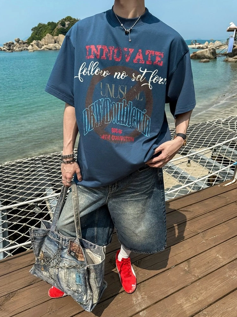 Light blue vintage wash wide-leg denim shorts styled with graphic shirt and tote bag on seaside dock