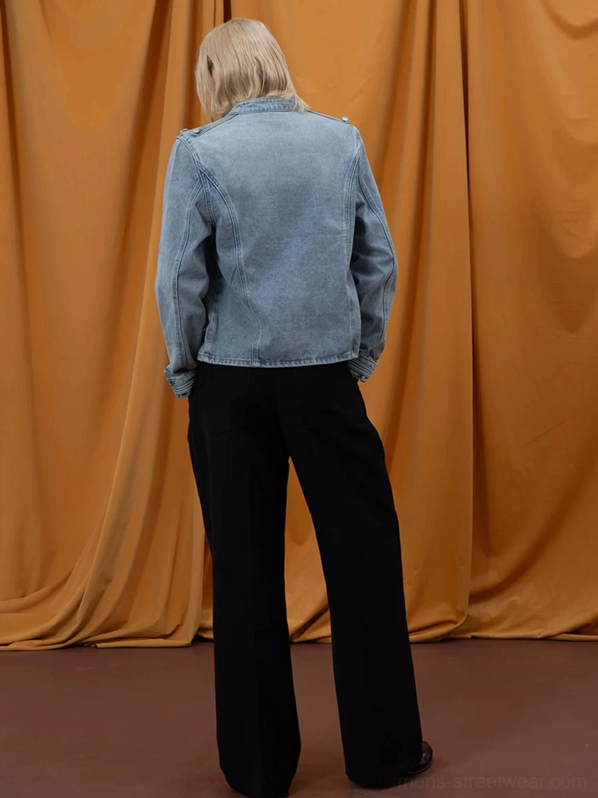 Back view of light blue washed denim military cropped jacket with clean back yoke and buttoned cuffs