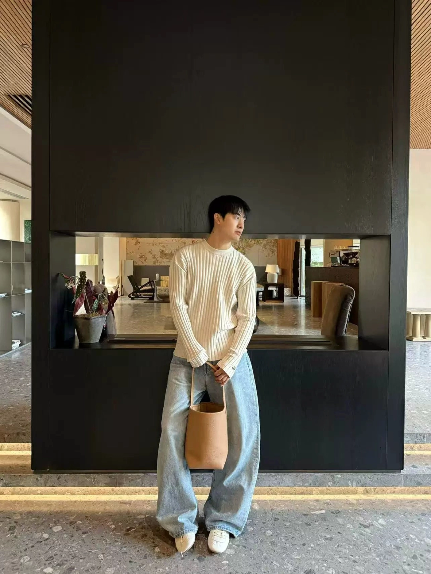 Side view of men's light blue washed wide leg denim jeans with a relaxed stacked hem and ribbed sweater streetwear styling