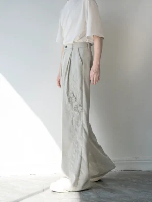 Left side full-body view of light gray embroidered wide-leg linen-blend trousers with high waist and raised floral embroidery on the thigh