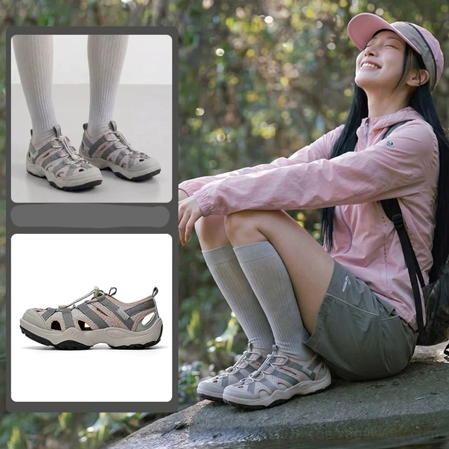 Light gray hybrid water hiking sandals worn in a shaded woodland setting, featuring breathable cutout mesh upper, black accents, and closed toe