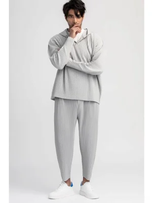 Light gray men's pleated cropped pants styled with a matching pleated hoodie and white sneakers in a modern Korean streetwear outfit