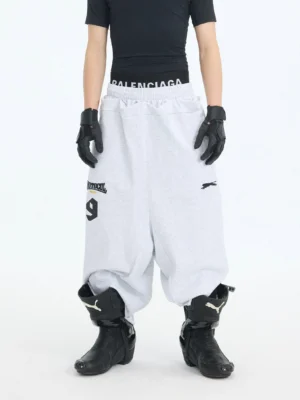 Light gray oversized 7/8 court shorts with wide-leg dropped-crotch fit, gathered elastic waist, and graphic streetwear detailing