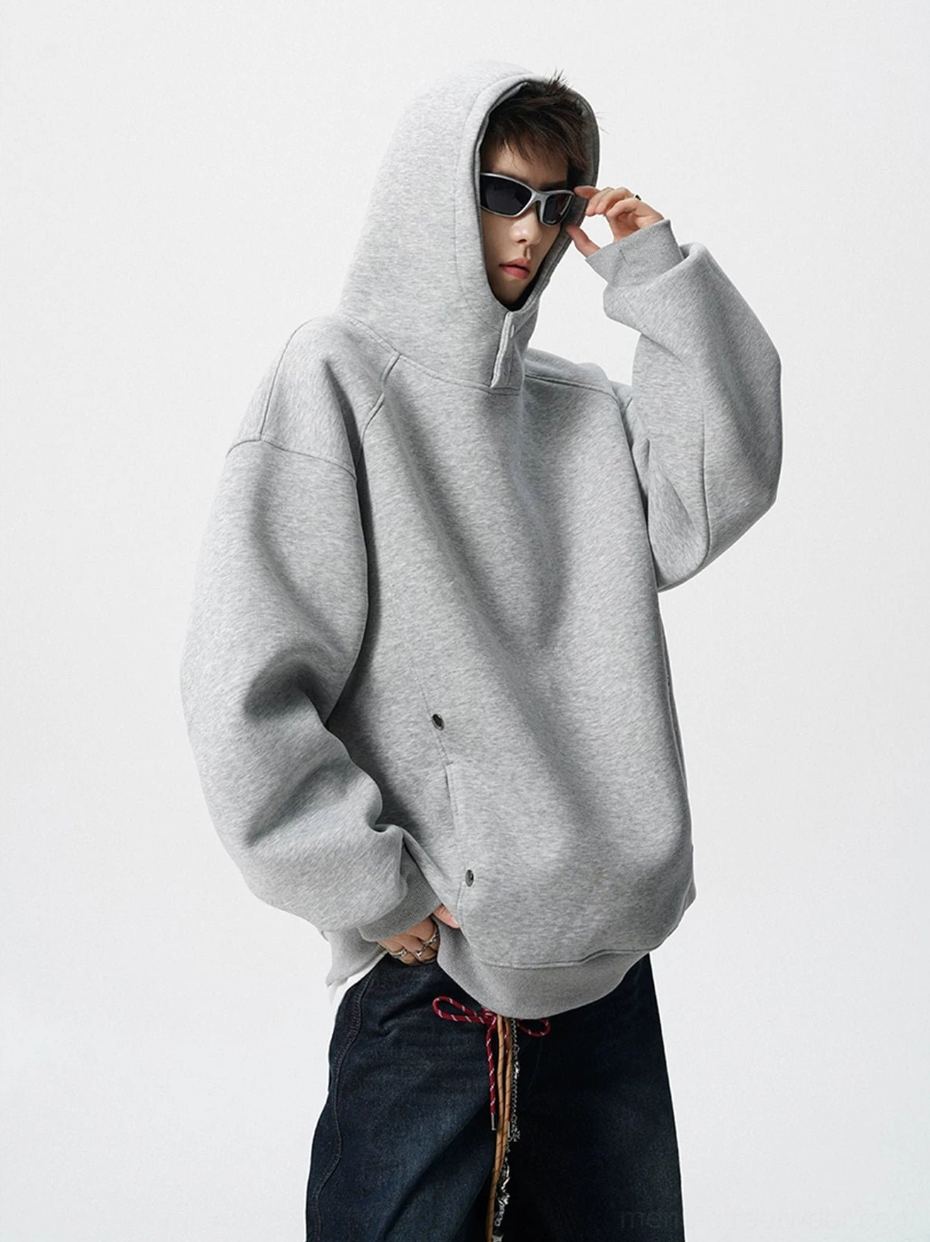 Side view of light gray oversized fleece hoodie showing attached hood drop shoulders and zip pocket streetwear details