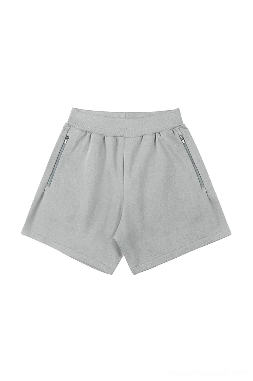 Light gray relaxed cotton blend sweat shorts with ribbed elastic waistband, angled zip pockets, and loose Korean streetwear fit on a white background