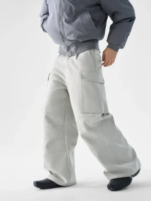 Light gray wide-leg structured pocket utility cargo pants for men shown in a front three-quarter studio view with pleated waist and oversized cargo pockets