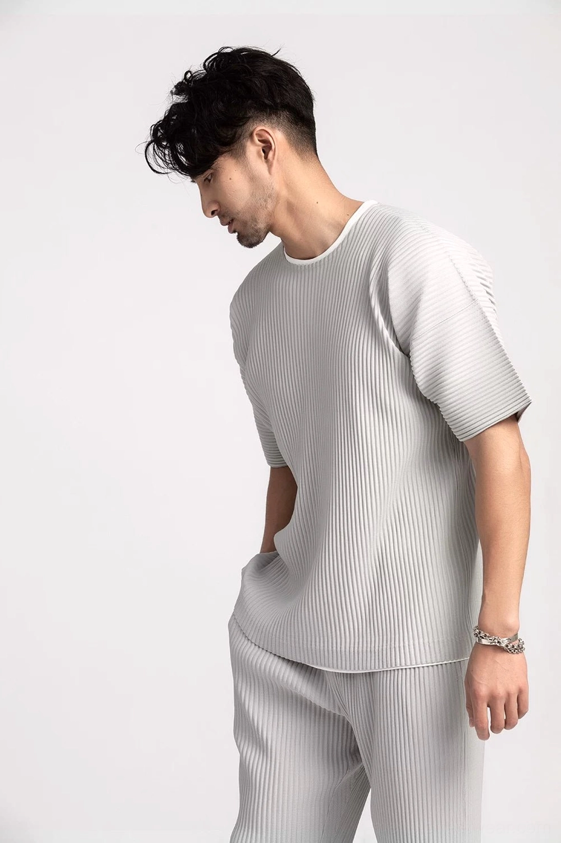 Light grey men's pleated two-piece streetwear outfit with boxy tee and matching straight-leg trousers