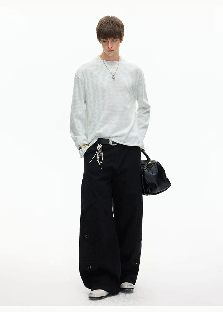 Rear three-quarter view of a relaxed light grey long sleeve tee paired with wide-leg trousers and a black handbag