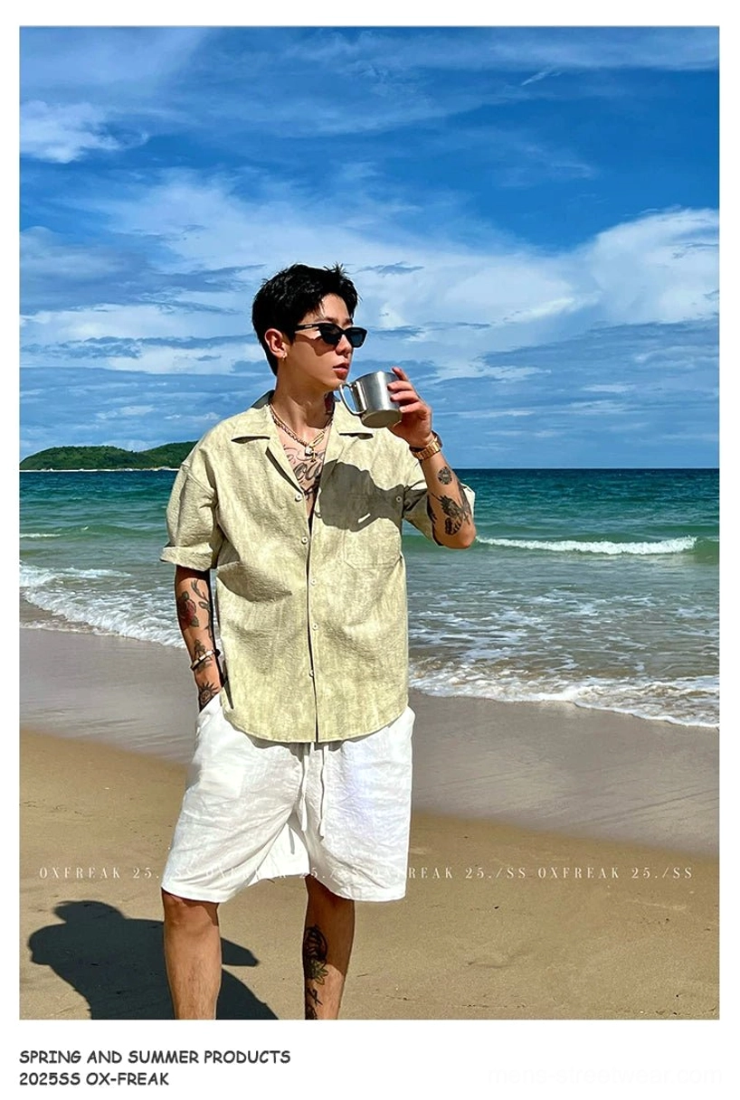Light Khaki relaxed short sleeve Cuban collar streetwear shirt worn with white shorts along a sandy shoreline