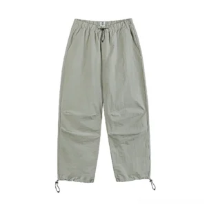 Light sage green relaxed parachute pants with wide legs elastic waist and adjustable drawstring hems