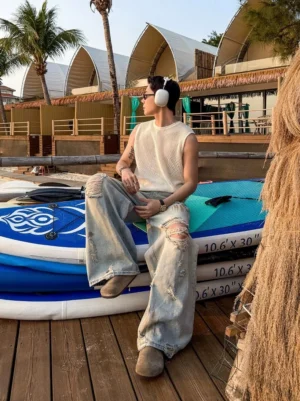 Side view of light blue distressed wide leg denim jeans showing oversized fit ripped knee and stacked leg streetwear styling
