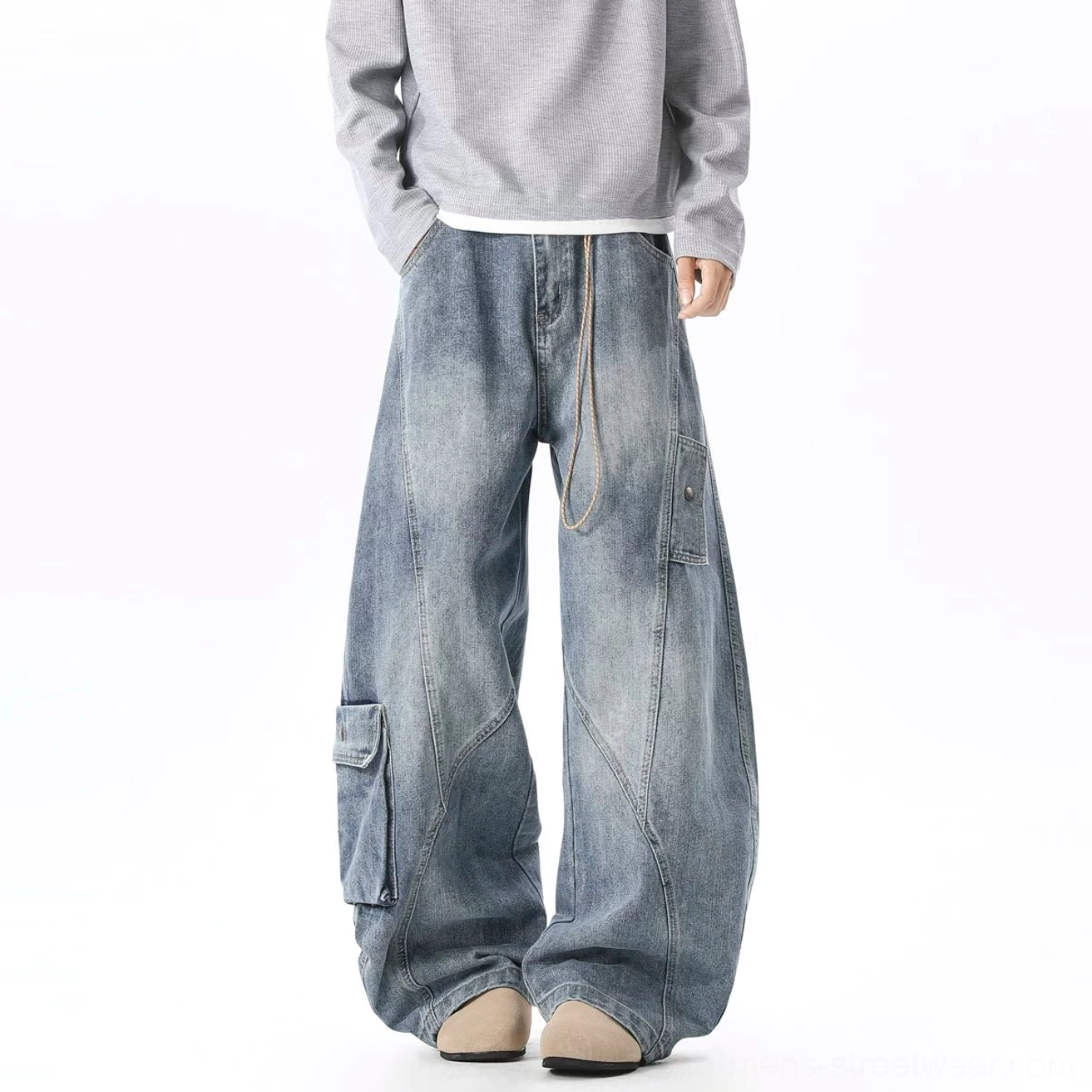 Light wash oversized cargo denim jeans shown from the rear three-quarter angle with curved stitching, side cargo pocket, waist rope detail, and stacked wide legs