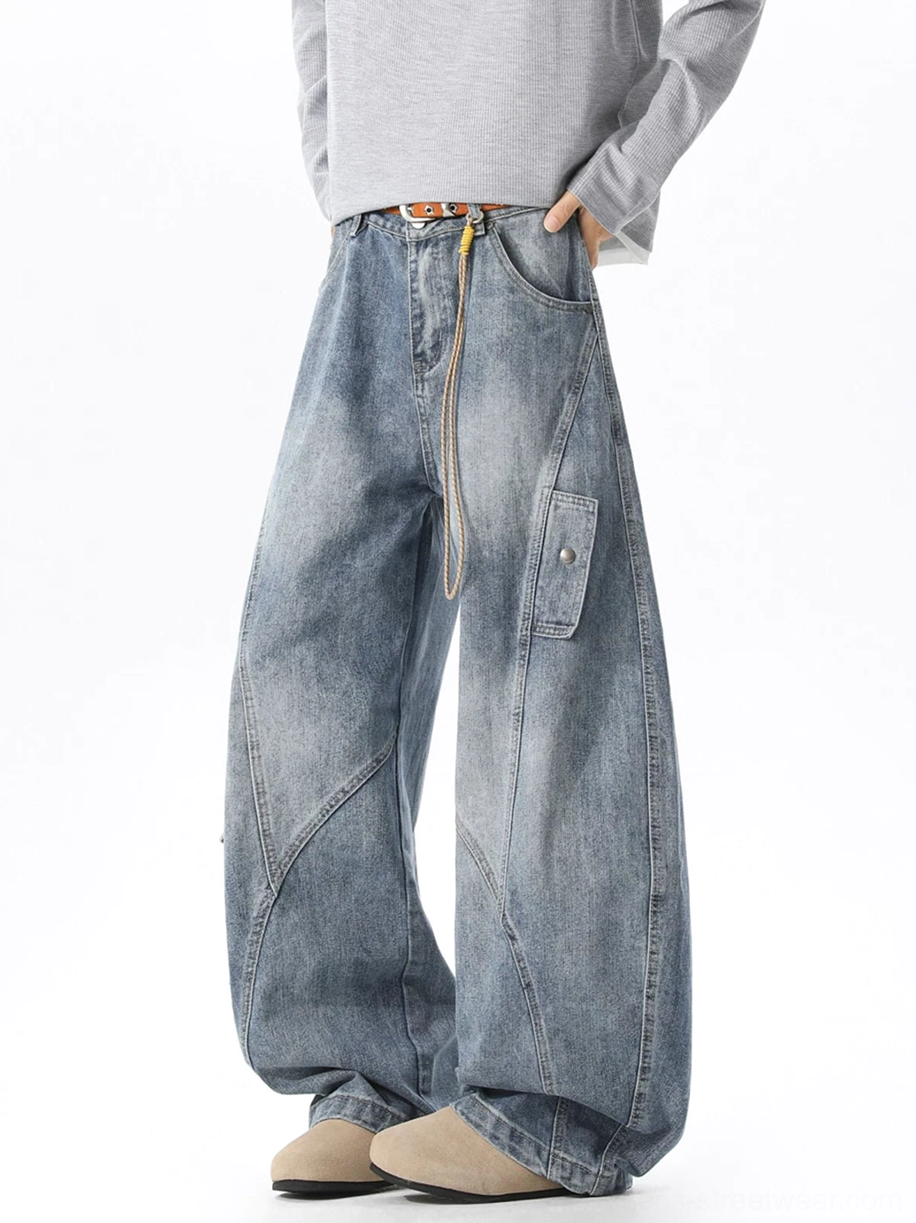 Light wash ultra-wide cargo jeans shown from a low front three-quarter angle with curved seams, waist rope detail, snap-button cargo pocket, and relaxed streetwear fit