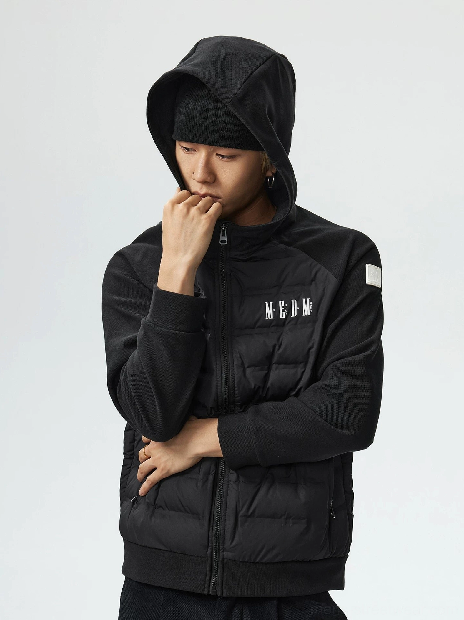 Black hybrid hooded goose down jacket close-up showing attached hood front zipper chest detail and raglan sleeve
