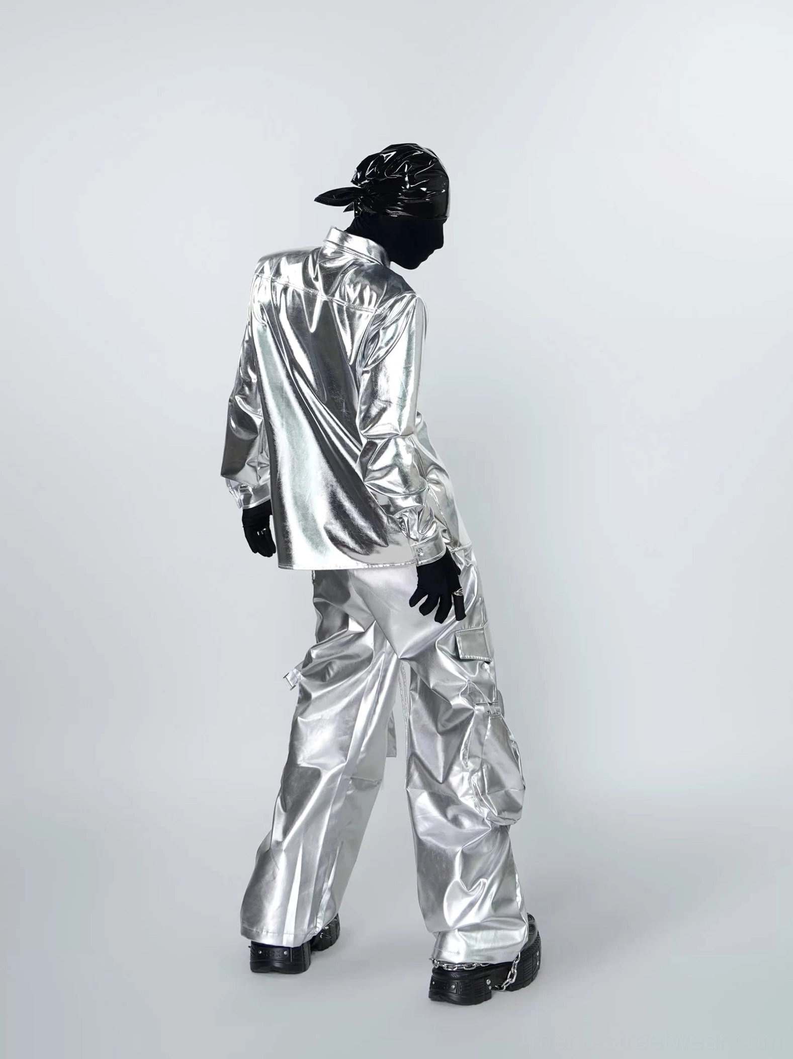 Rear three-quarter view of a metallic silver long sleeve shirt with a clean back silhouette styled with wide-leg cargo pants and platform shoes