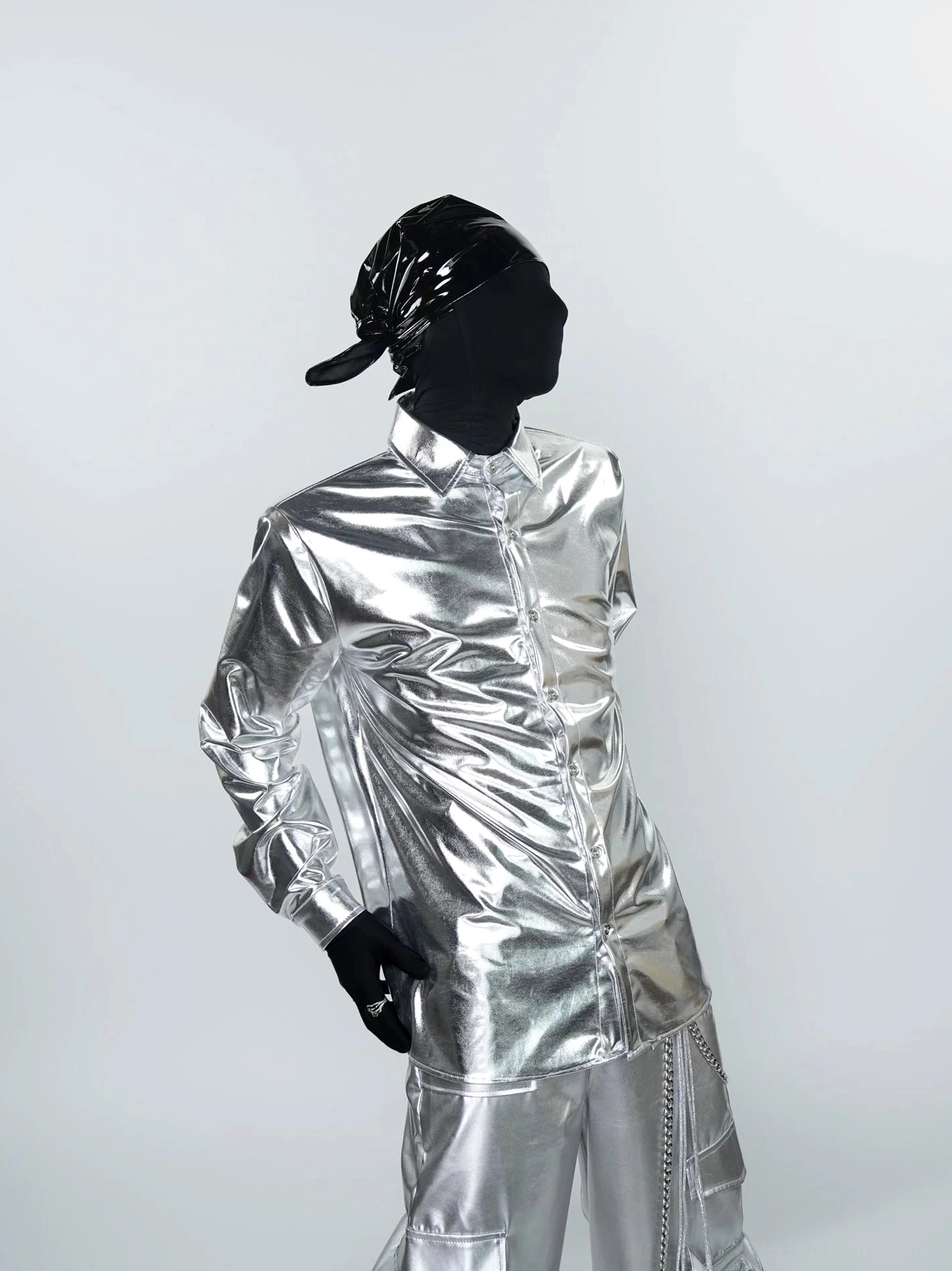Three-quarter side view of a liquid metal silver button-front shirt showing its relaxed fit, reflective fabric, and futuristic Korean streetwear styling