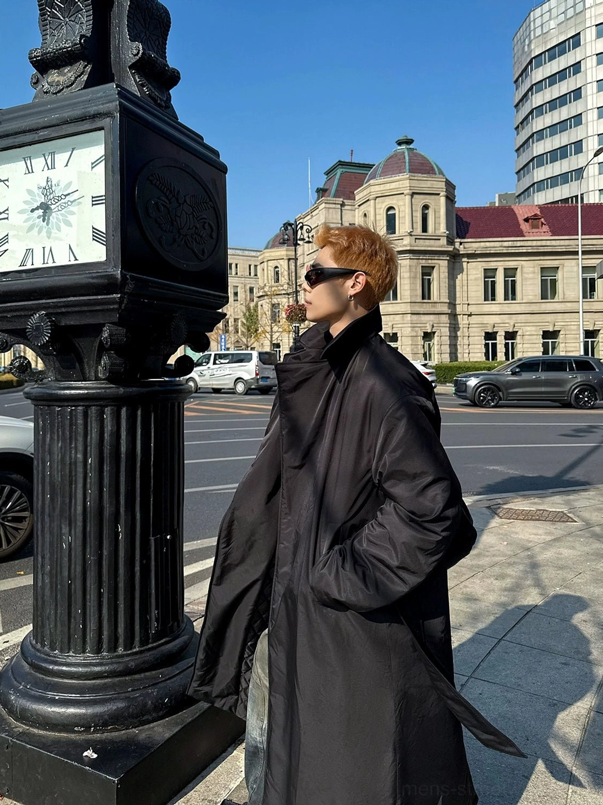 Side profile of a long black padded overcoat with high fold over collar hidden waist belt and oversized winter streetwear silhouette