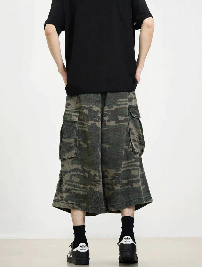 Rear full-body view of loose camouflage cargo cropped shorts showing the layered hem and rear utility pocket styling