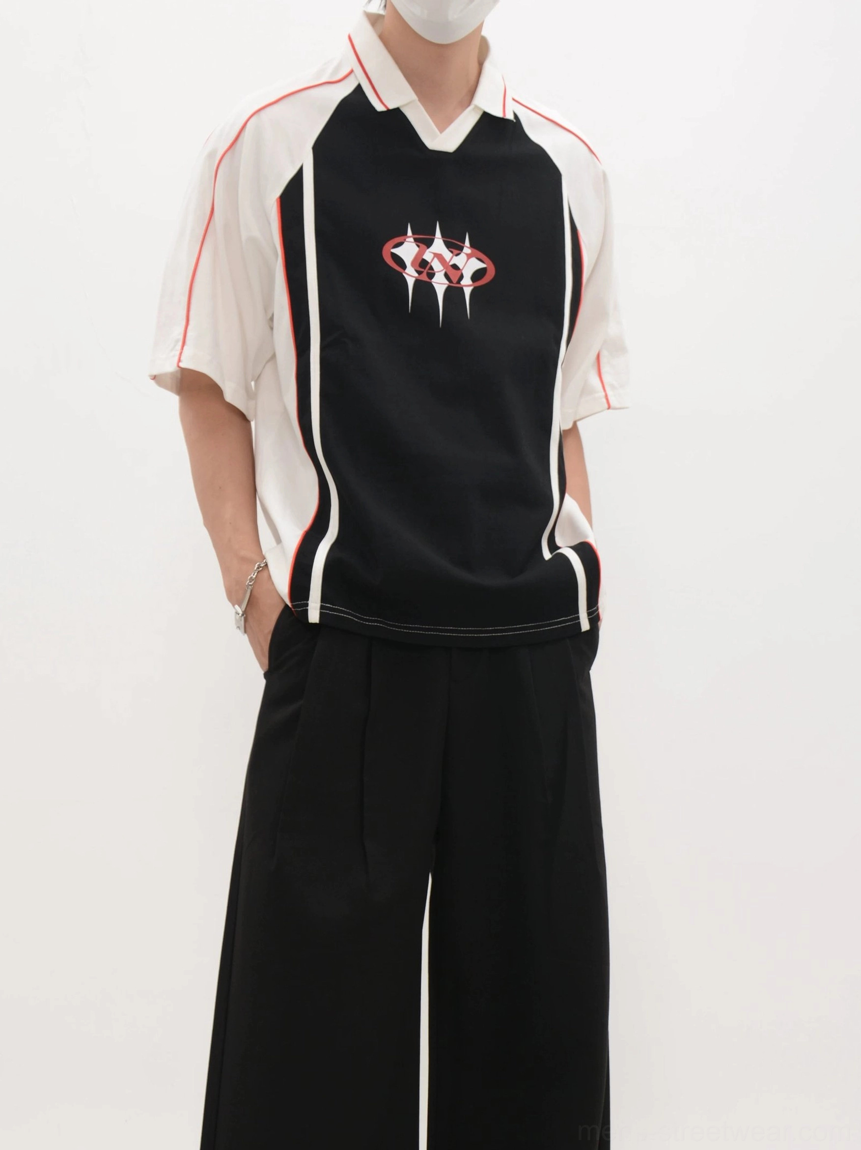 Loose fit black soccer jersey shirt with white sleeves, contrast side stripes, red trim, and graphic chest detail