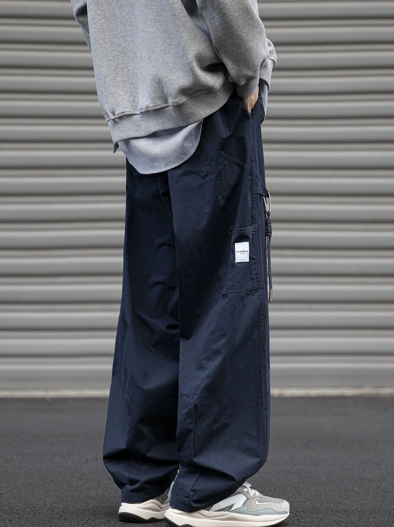 Back side standing view of dark navy loose fit cargo pants with clean wide leg construction and utility pocket detail