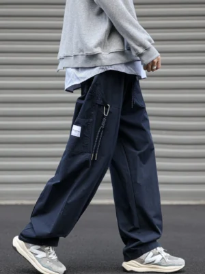Dark navy loose fit utility cargo pants with oversized drawstring side pocket shown in a side walking streetwear outfit