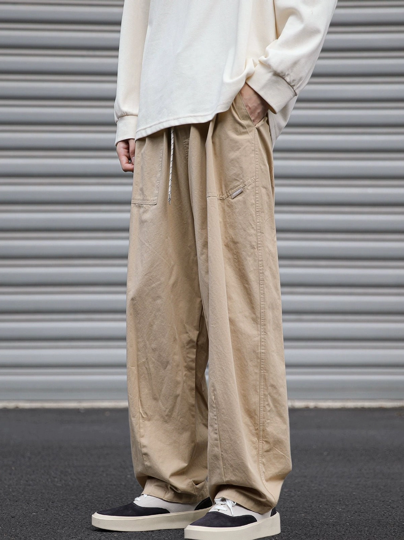 Front view of khaki loose fit utility cargo pants with elastic drawstring waist and wide straight leg silhouette