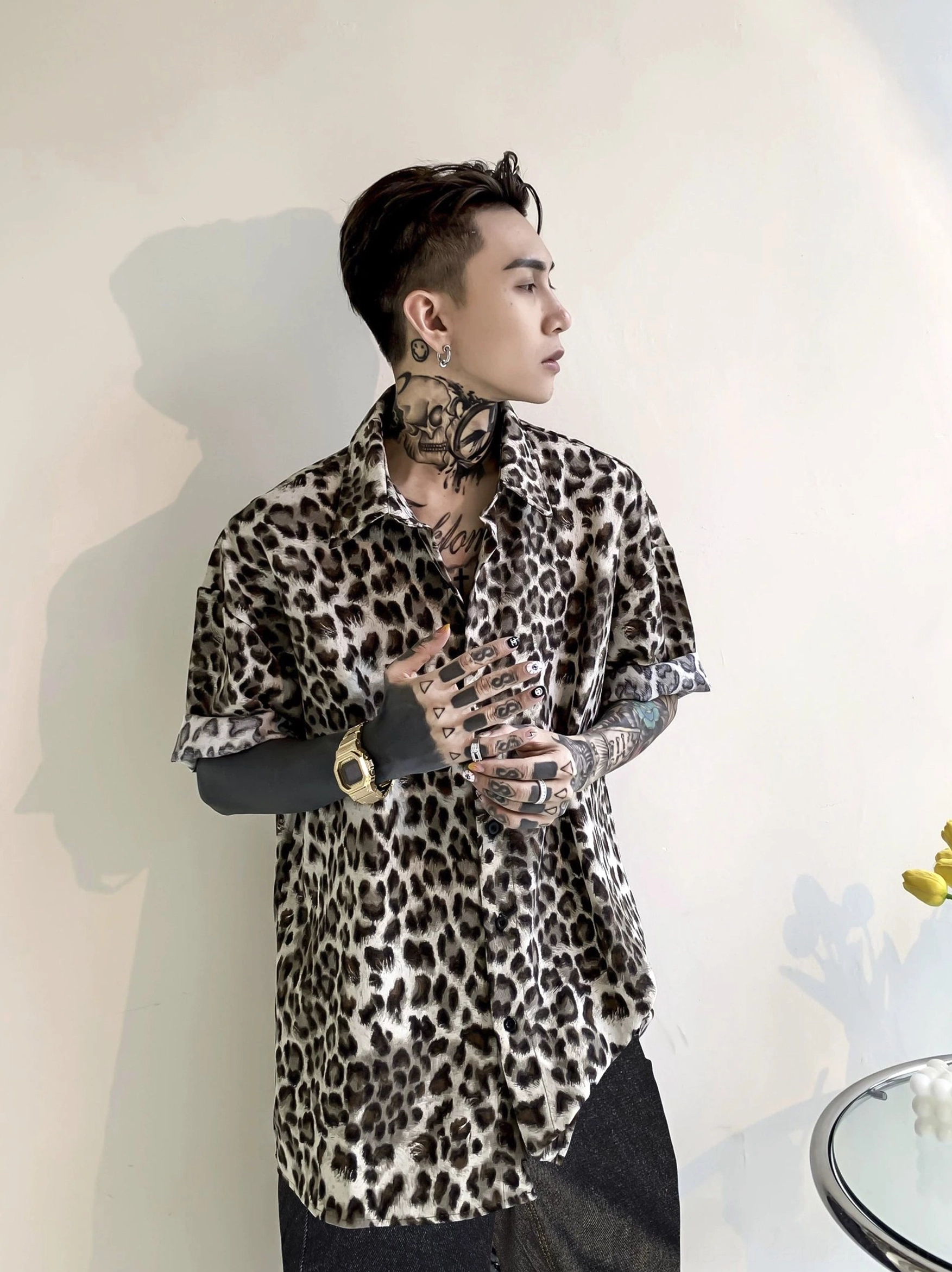 Side three-quarter view of a loose leopard print satin shirt styled with dark wide-leg pants for an East Asian streetwear outfit