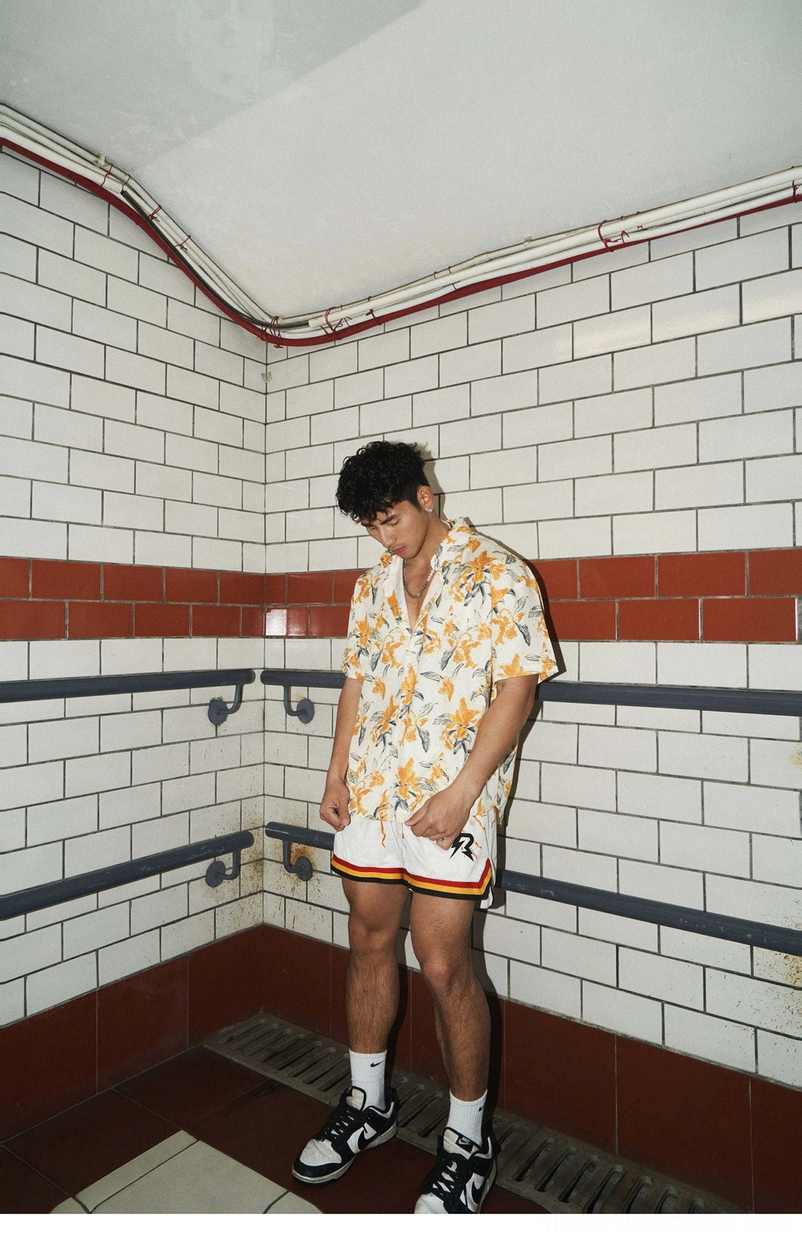 Side angle full-body view of a model wearing a loose tropical floral camp shirt with a casual Korean streetwear silhouette