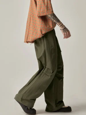 Army green loose wide-leg drawstring cargo pants shown from a rear side angle with crinkled lightweight nylon fabric and relaxed Korean streetwear styling