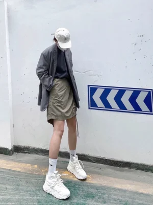 White MagmaFlow Sculpt leather chunky sneakers worn with a grey blazer, khaki shorts, white cap, and crew socks in an urban Korean streetwear outfit