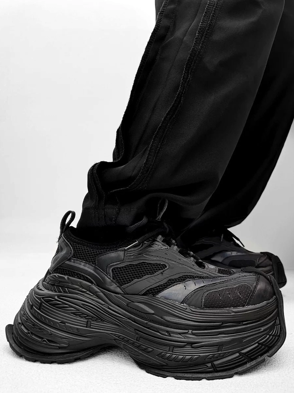 Matte black chunky platform dad shoes with retro silhouette textured serrated sole and futuristic streetwear design