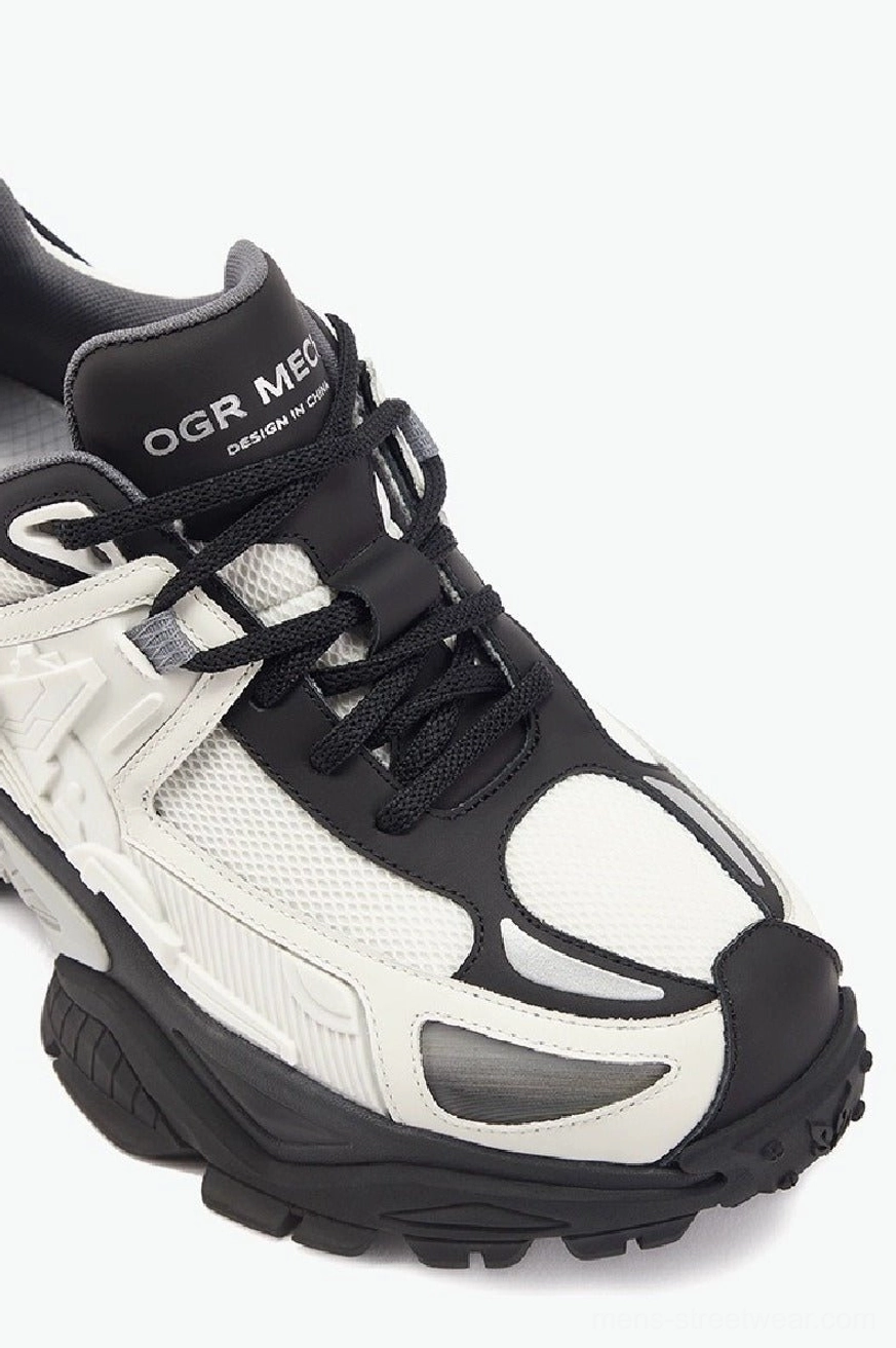Close-up front three-quarter view of futuristic mecha platform sneakers with layered construction, mesh panels, and rugged lug rubber outsole