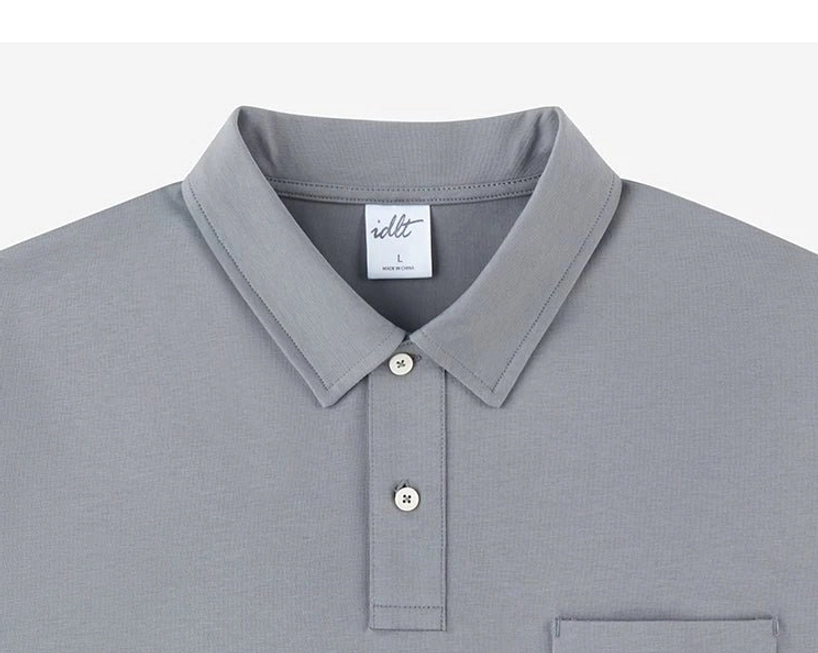 Close up of medium grey technical knit polo collar with two button placket, chest pocket, and soft smooth fabric texture