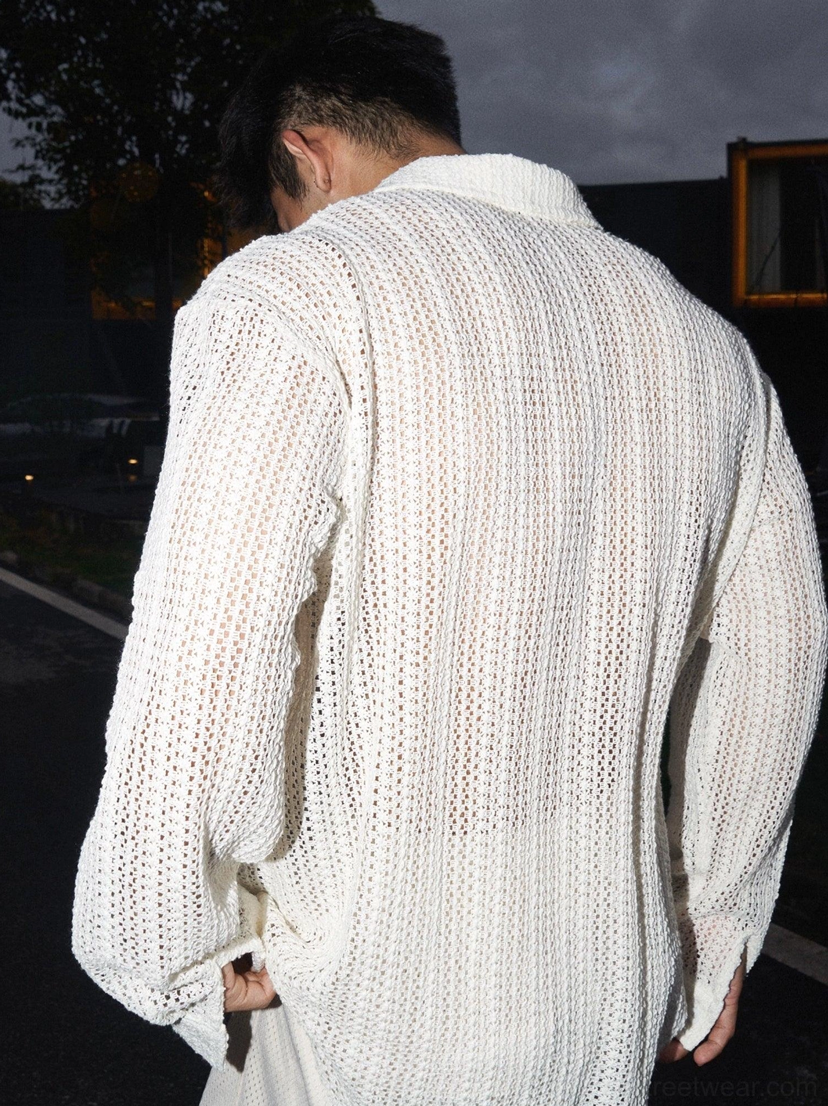Back view of men's apricot long-sleeve open-knit crochet shirt showing relaxed fit curved hem and hollow knit texture