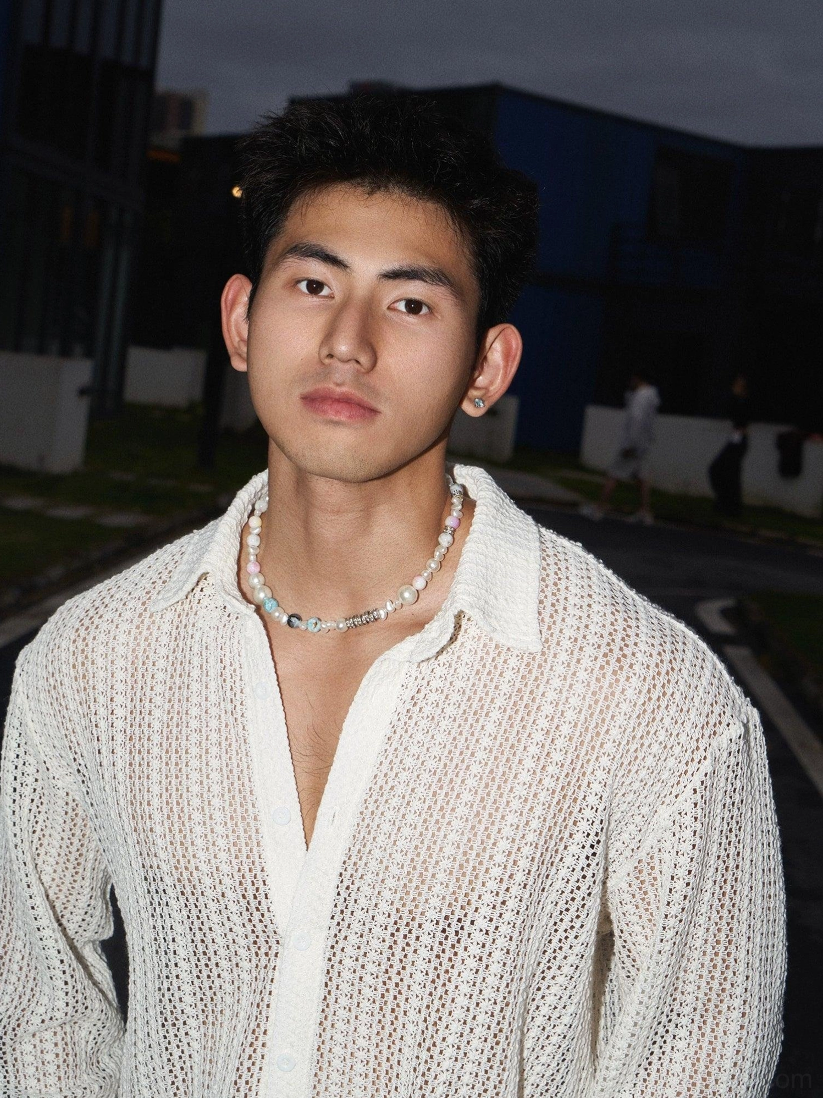 Close-up of men's apricot long-sleeve open-knit crochet shirt with spread collar unbuttoned neckline and hollow woven texture