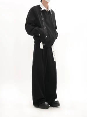 Side view of black collarless asymmetric button blouson jacket with relaxed drop shoulders and cropped streetwear fit