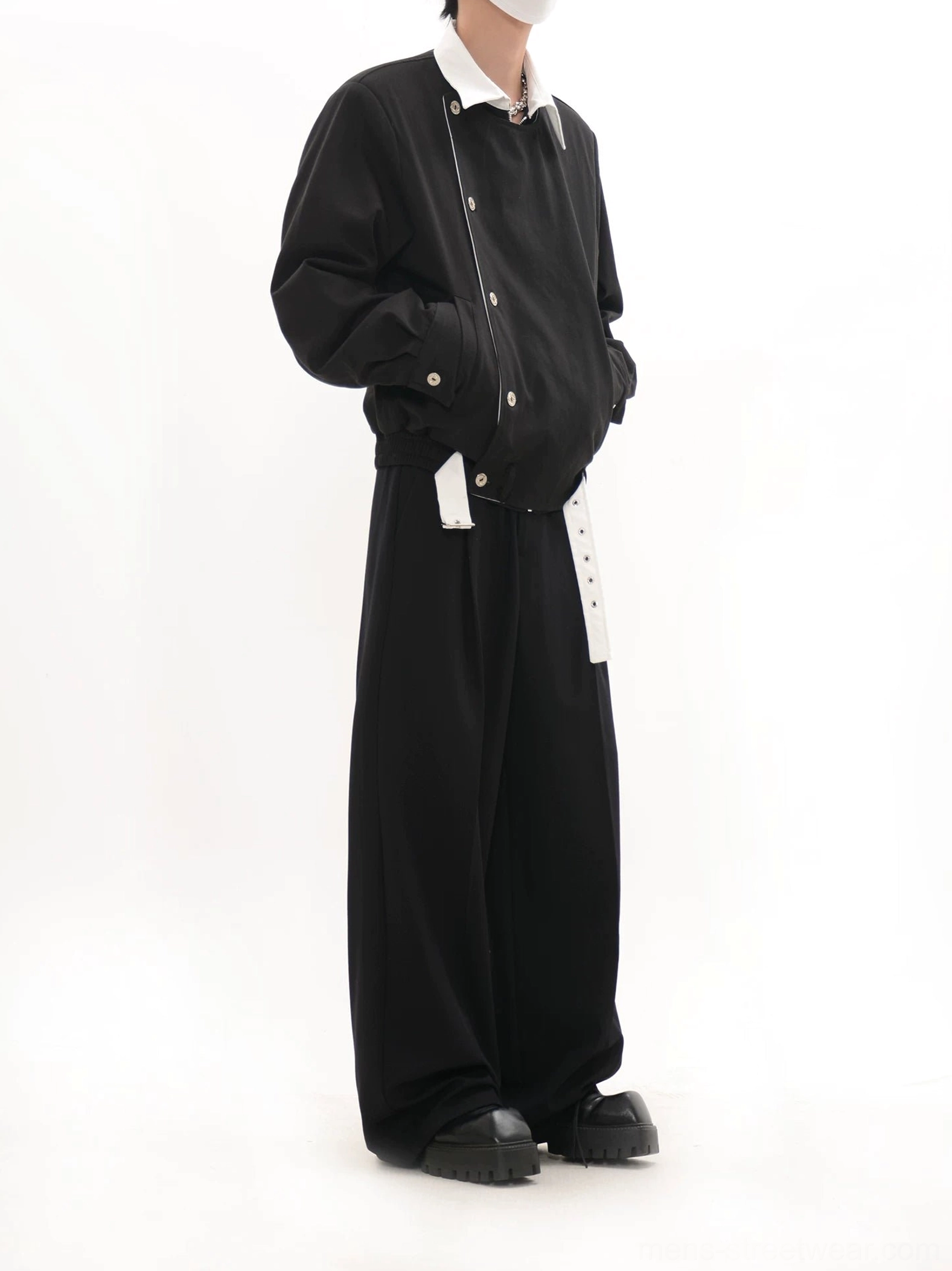 Side view of black collarless asymmetric button blouson jacket with relaxed drop shoulders and cropped streetwear fit