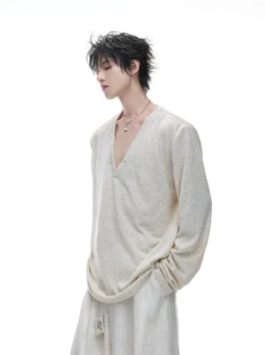 Men's beige sheer deep V-neck long sleeve knit top shown in side view with relaxed drape and off-white wide leg trousers
