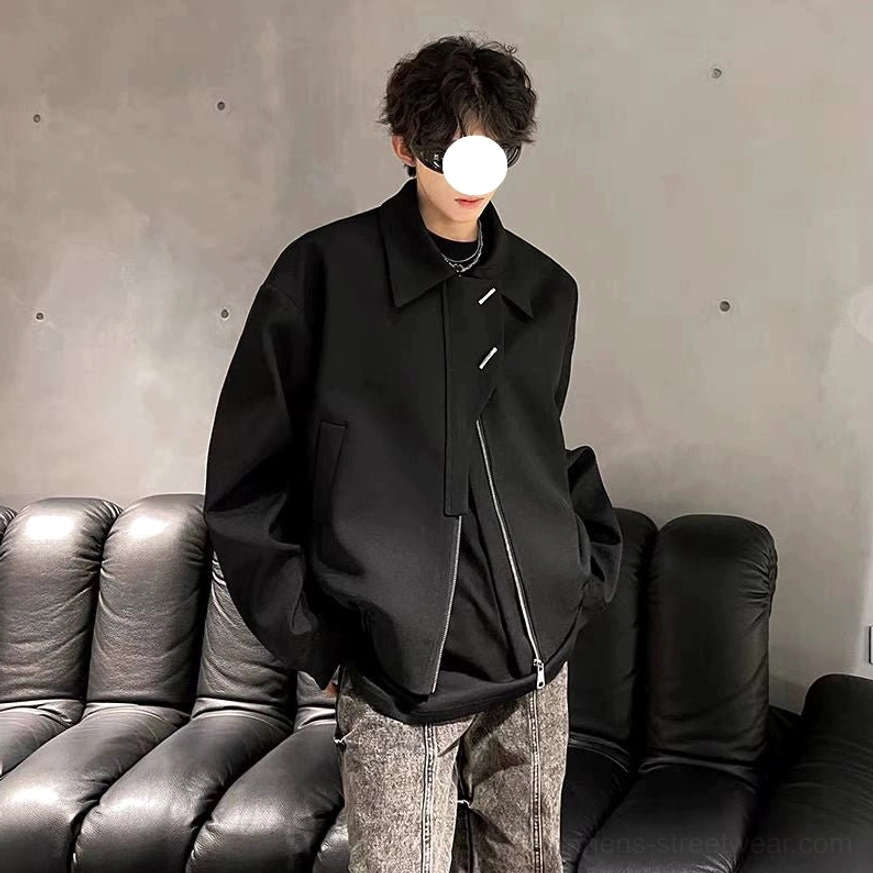 Men's black asymmetrical zip bomber jacket styled with patterned wide-leg jeans in a modern streetwear outfit