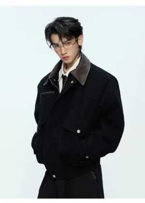 Men's black bomber jacket with brown contrast collar chest zipper pocket and metal snap front three-quarter view