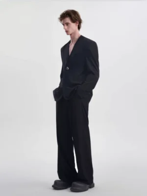 Side view of men's black collarless blazer and relaxed wide-leg trousers with silver button detail