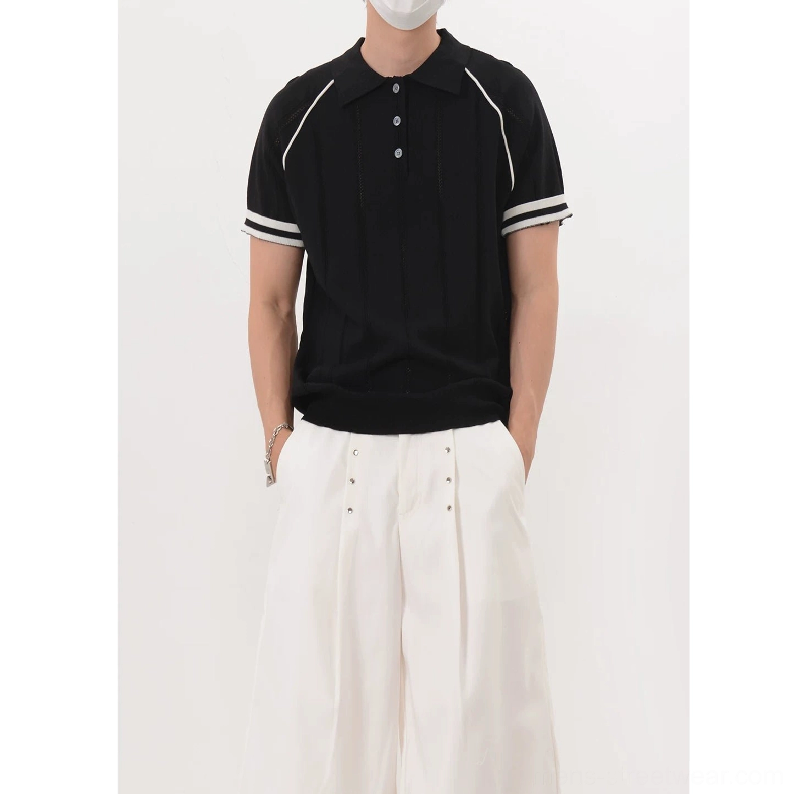 Men's black contrast trim ribbed knit polo shirt styled with white wide-leg trousers front three-quarter view
