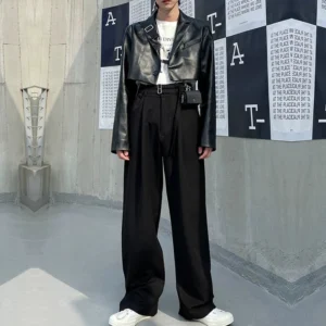 Men's black high waist double buckle wide leg pleated trousers styled with cropped leather jacket and white sneakers