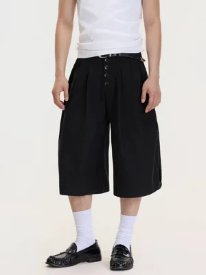Front full-body view of men's black drop-crotch wide-leg culottes styled with a white tank top, white crew socks, and black leather loafers