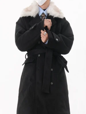 Close-up of men's black longline coat featuring white faux fur collar, double-breasted buttons, adjustable waist belt and cuff tabs