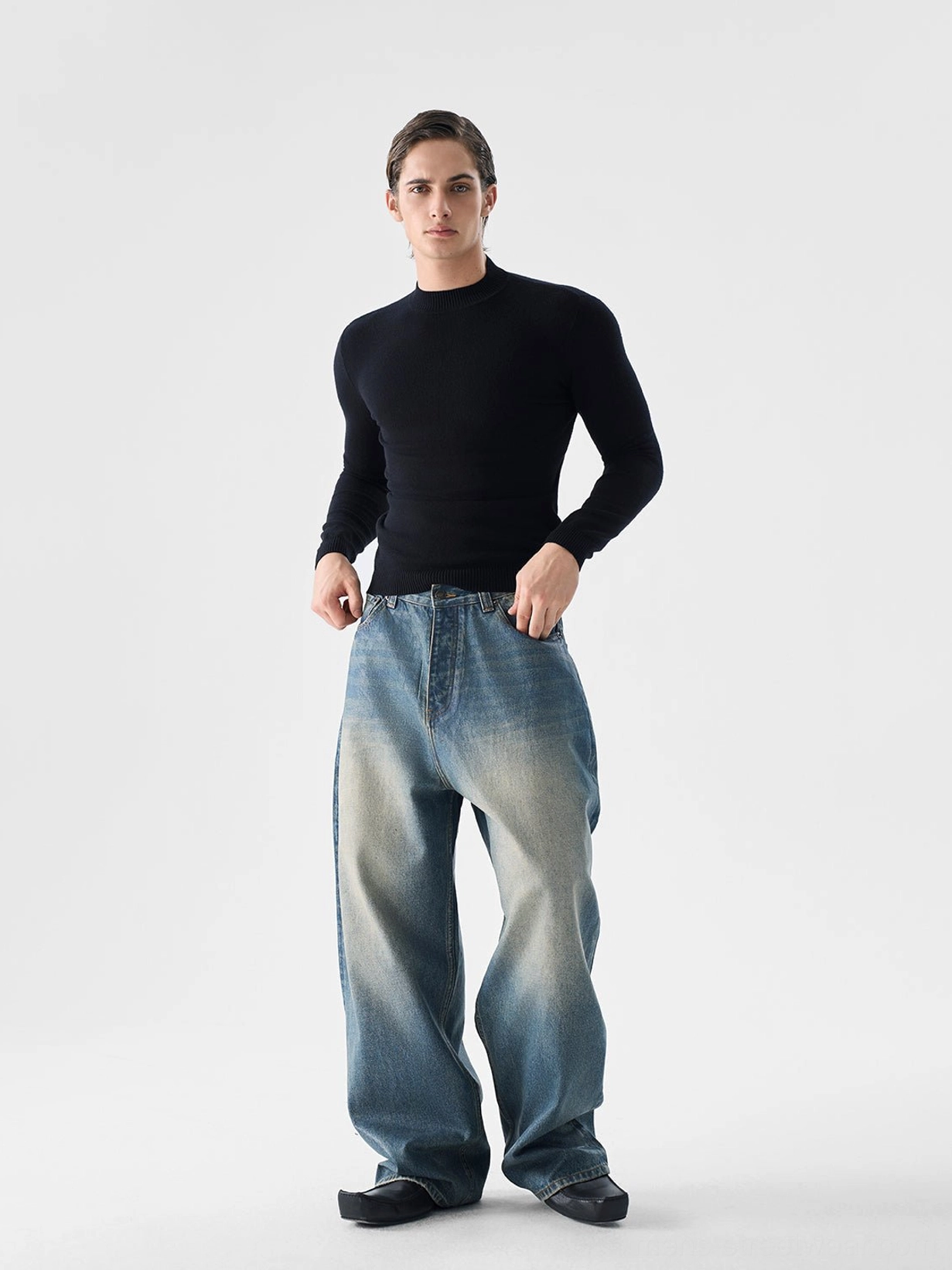 Men's black fitted mock neck knit sweater with ribbed collar cuffs and hem styled with relaxed faded denim