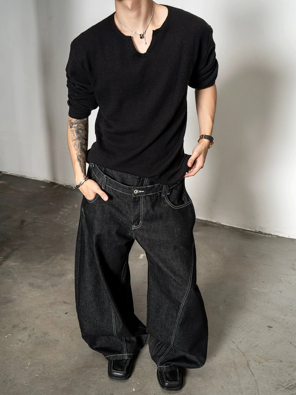 Black relaxed fit men's notch neck knit sweater with soft textured finish and dark wide leg jeans